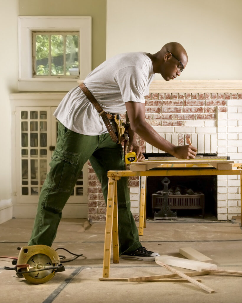 African American carpenter working on a woodworking project for the 'About Us' section.